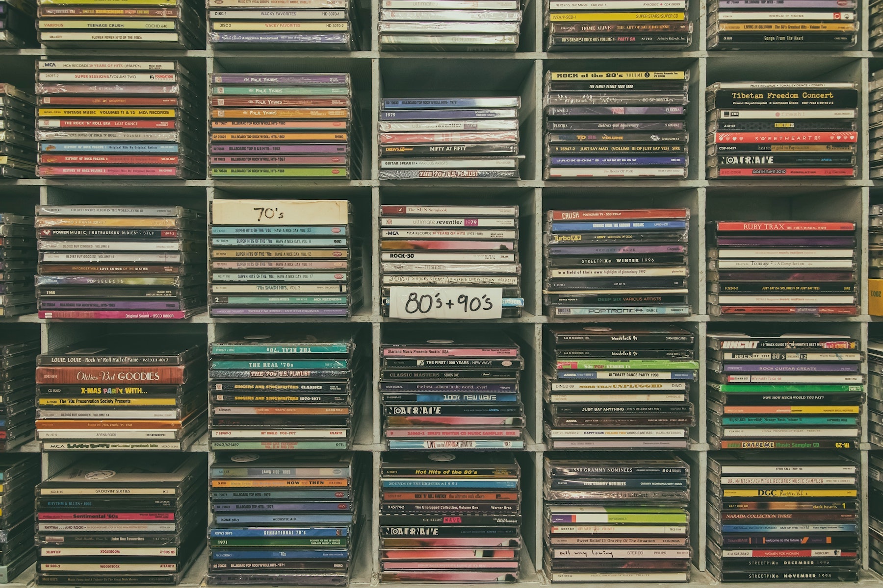 Vari cd sistemati dentro uno scaffale divisi tra anni 70, 80 e 90. Dovessi scegliere, meglio cd o vinile?